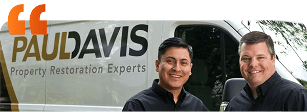 Paul Davis restoration team smiling in front of a company truck